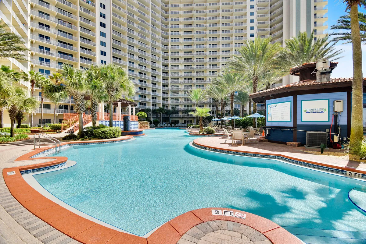 A resort-style swimming pool surrounded by palm trees, poolside lounge chairs, and a shaded cabana. The pool area exudes a lively, social vibe ideal for mingling with friends or unwinding between adventures. The scene hints at resort amenities like the lagoon pool and poolside bar service featured in the section.