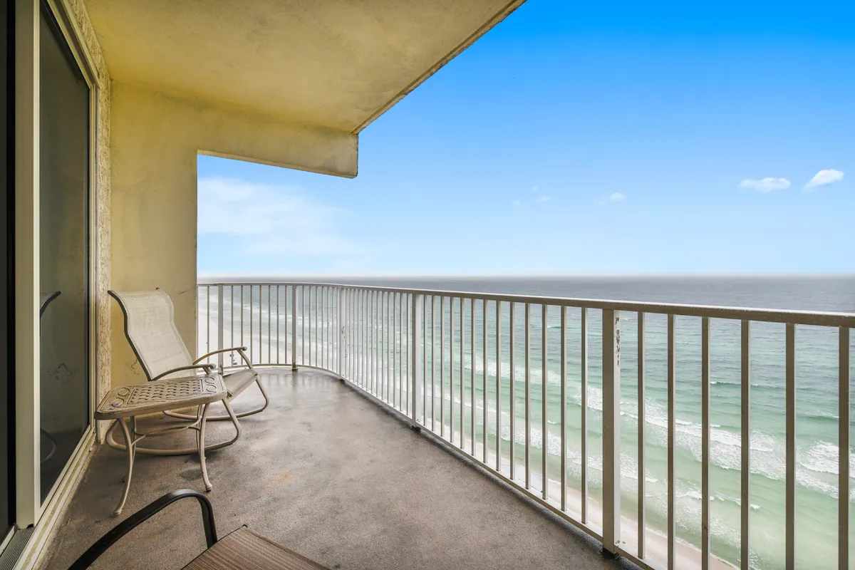 This image features a private wraparound balcony overlooking the Gulf, with two outdoor chairs positioned to take in the panoramic ocean view. The balcony’s metal railing frames the endless white sand and rolling waves below, creating a serene setting for morning coffee or group gatherings.